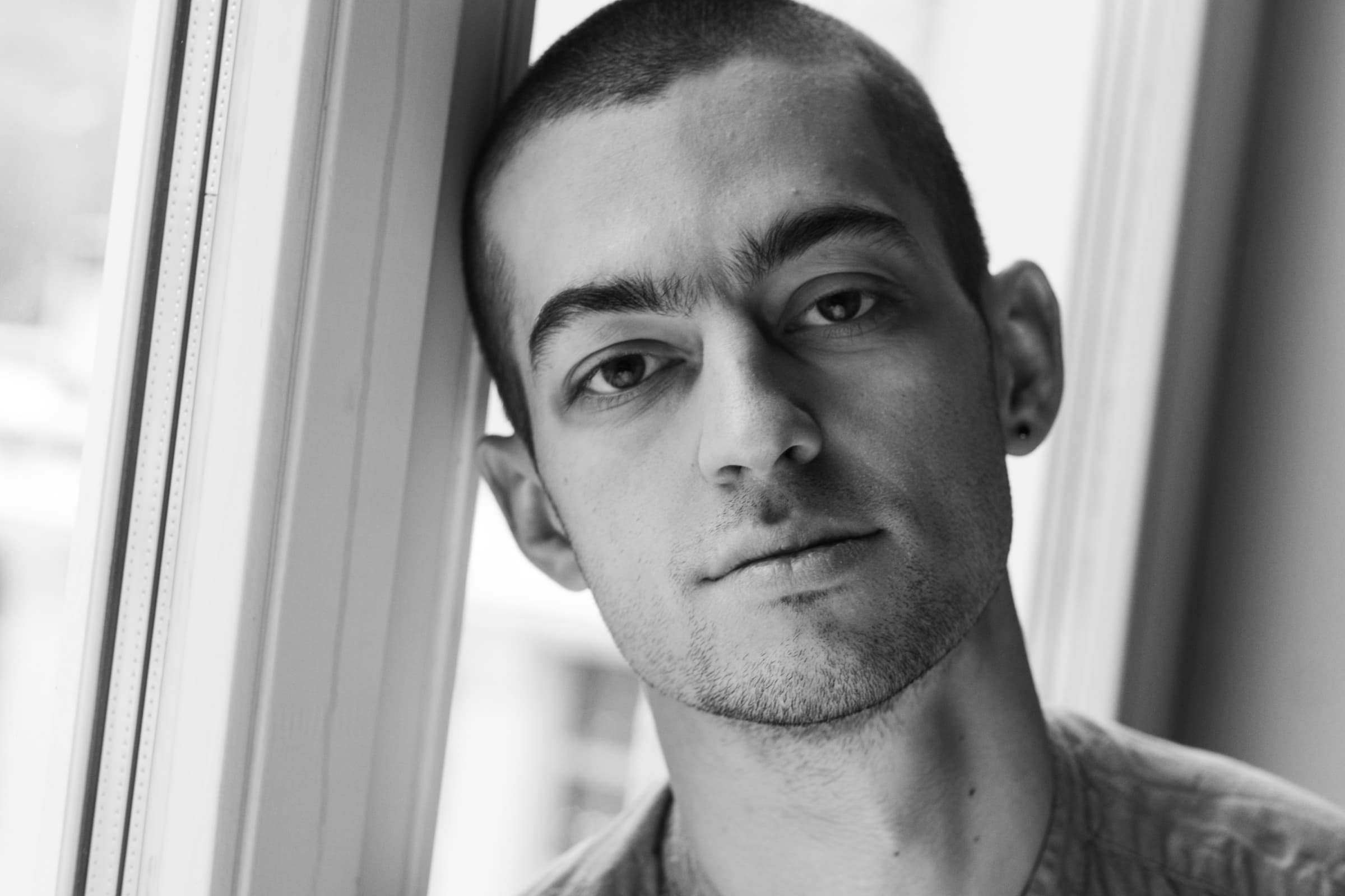 Black-and-white portrait of Kolya Bagdasaryan beside a window.